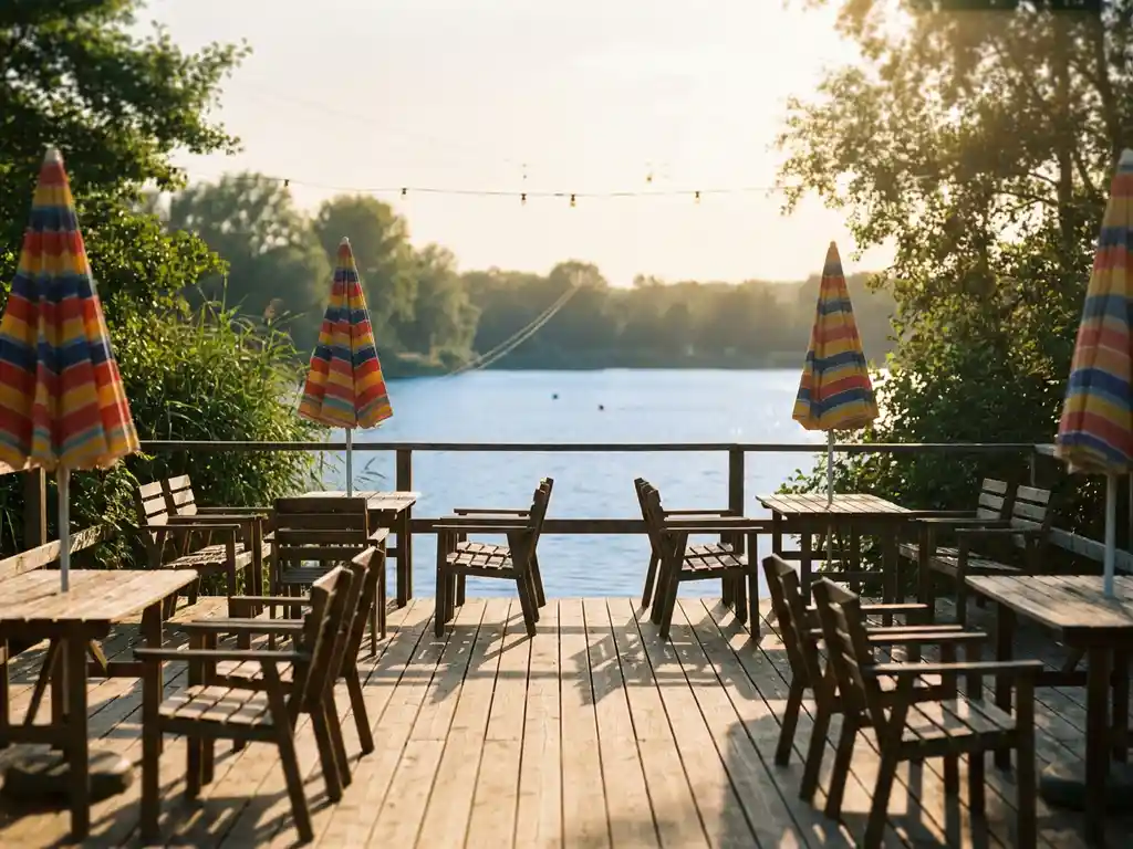 Leeg houten terras met kleurrijke parasols aan een kalm blauw meer, gouden namiddaglicht door groene bomen.